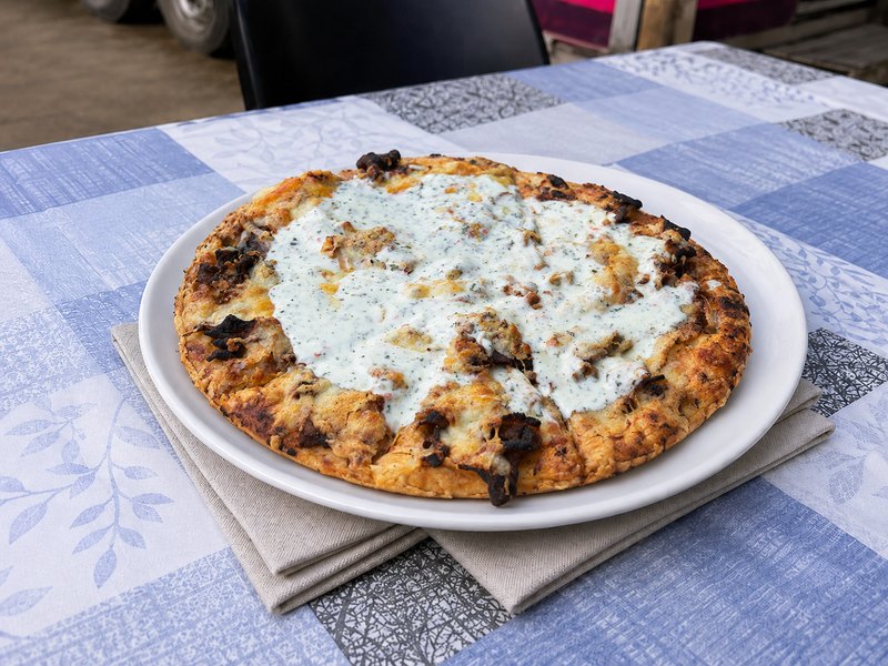 Dönerpizza mit Kräutersoße auf weißem Teller